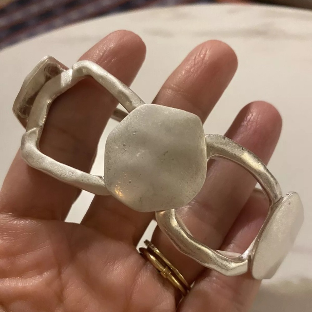 Silver tone. 
Hammered metal 
Stretch band. 
Statement piece